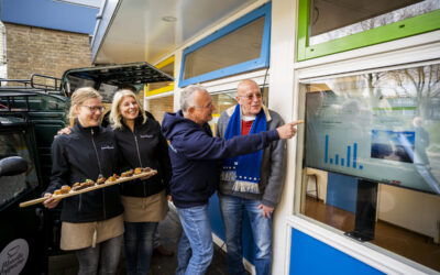 Wethouder Duurzaamheid Nico van Veen kijkt samen met een vrijwilliger van Zonkracht Capelle naar het dashboard met de opgewekte enerige