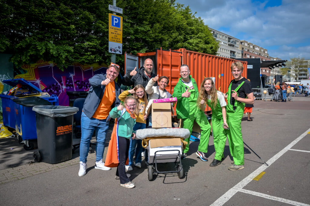 Organisatie en kinderen staan met onverkochte handel bij de inzameplek om spullen naar de kringloop te brengen