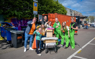 Organisatie en kinderen staan met onverkochte handel bij de inzameplek om spullen naar de kringloop te brengen