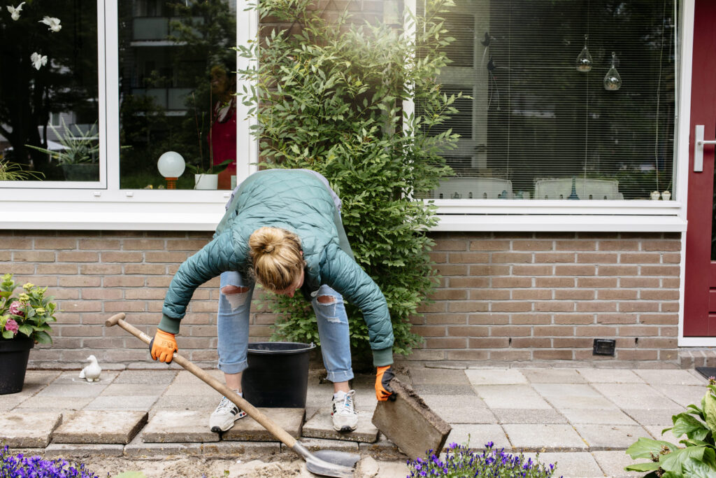 Bewoner haalt tegels uit de tuin om te vervangen met planten en bloemen.