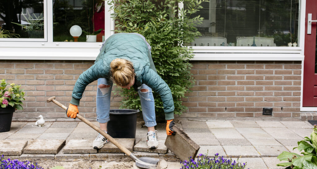 Bewoner haalt tegels uit de tuin om te vervangen met planten en bloemen.