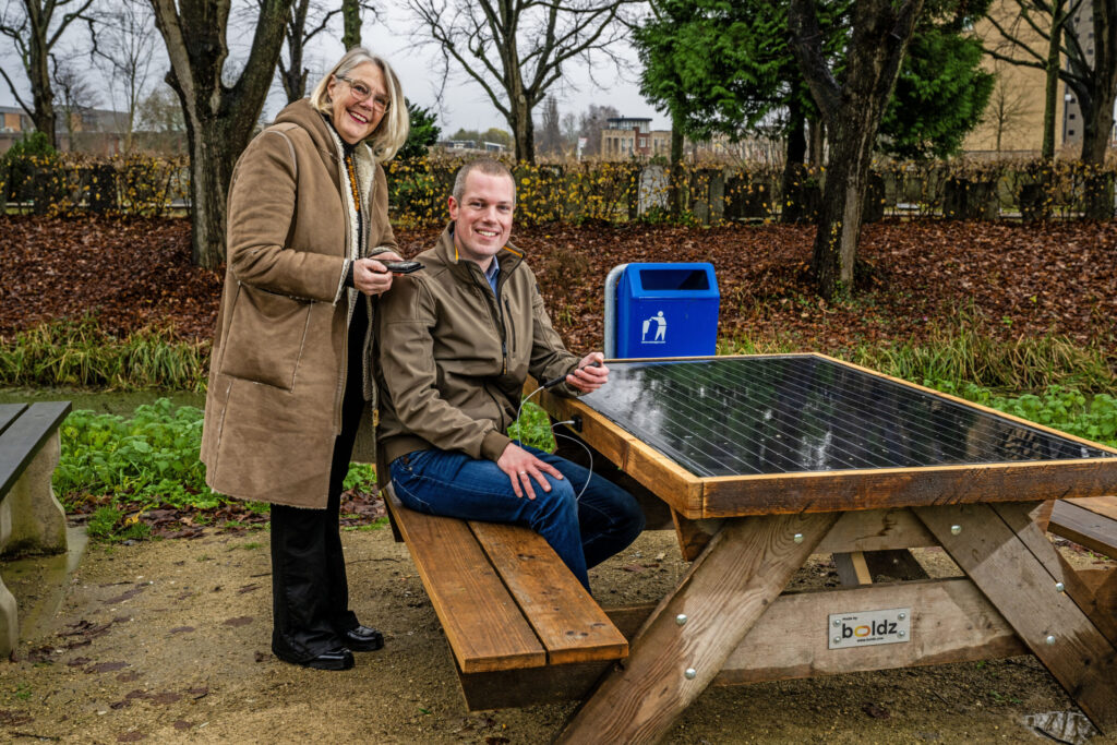 Sjoerd Geissler (Wethouder Duurzaamheid) en Leonie van Haren (Programmamaner Sterk Techniek Onderwijs) laden telefoon op aan powerbank van hergebruikt zonnepaneel