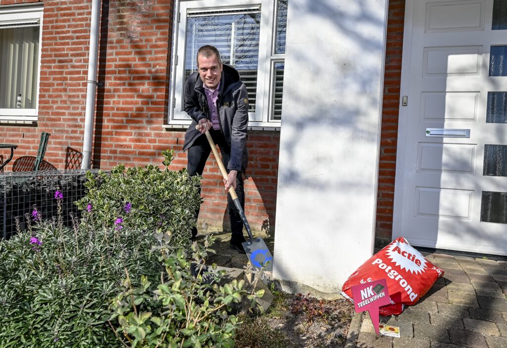 Wethouder Sjoerd Geissler wipt tegels in Capelse tuin voor het NK Tegelwippen