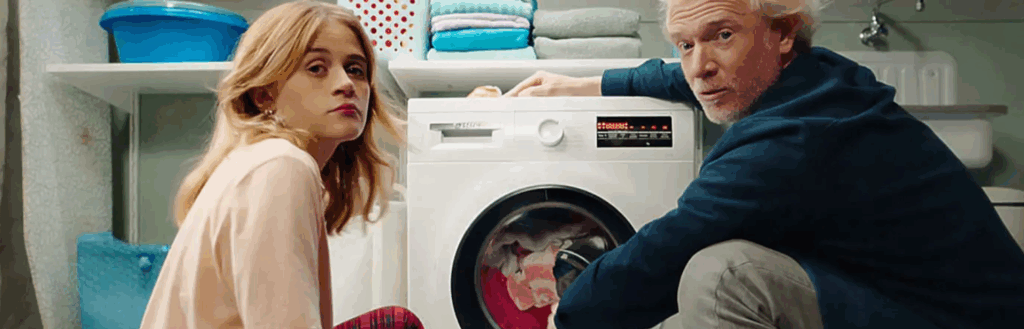 Man en vrouw zitten bij een wasmachine.