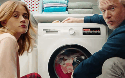 Man en vrouw zitten bij een wasmachine.