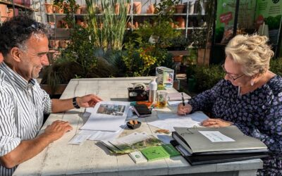Een inwoner zit met een tuinontwerper aan tafel voor een tuinschets