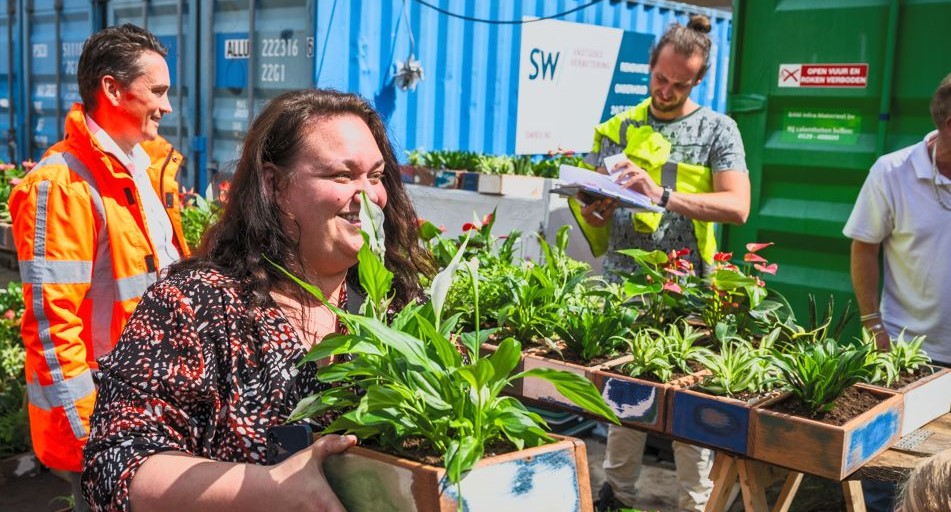 Bewoners van de Florabuurt ontvangen een plant voor hun balkon.