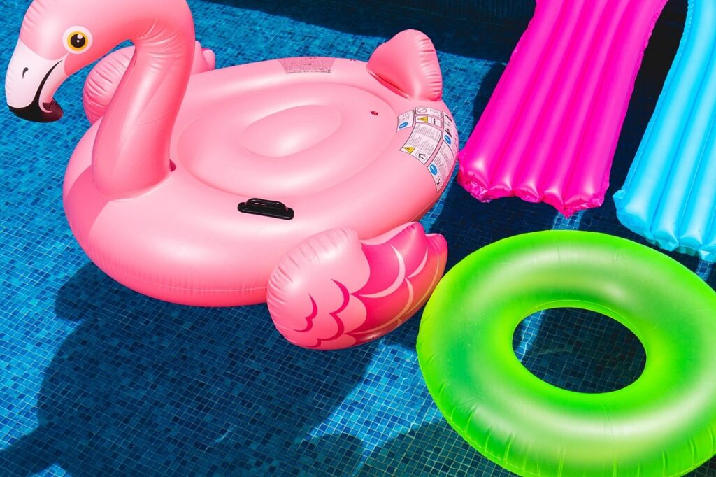 Opblaasluchtbedden, zwemband en opblaad flamingo in het zwembadwater