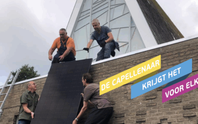 Vier mannen tillen een zonnepaneel op het dak van de kerk.