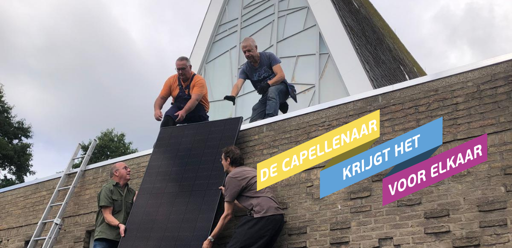 Vier mannen tillen een zonnepaneel op het dak van de kerk.