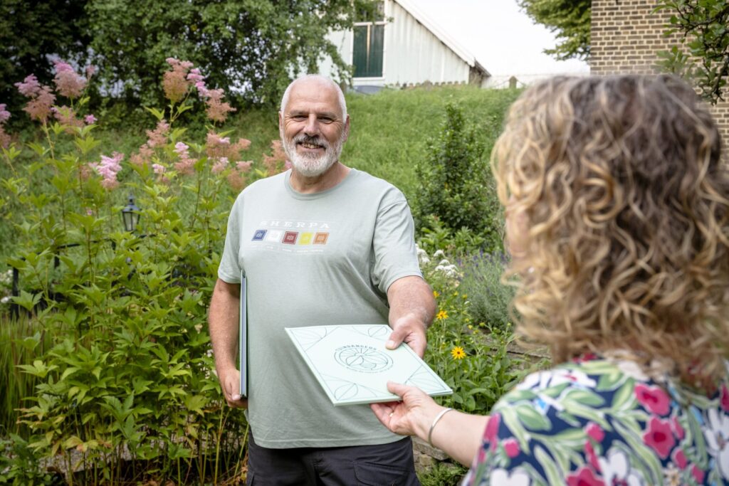 Tuinranger geeft map met informatie aan een bewoner