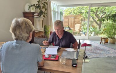 Energie adviseur aan de eettafel in gesprek met een bewoner.