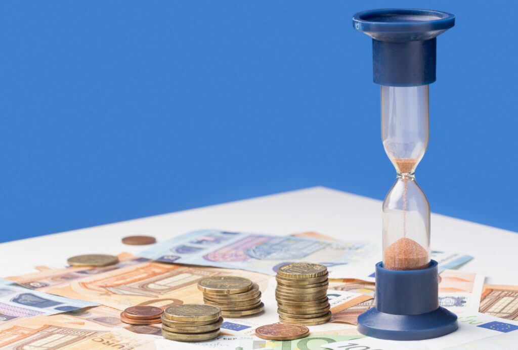 Papiergeld en munten en een zandloper