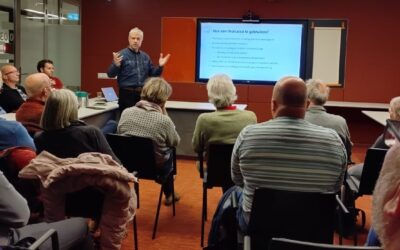 Johan Monster van het ECC geeft een presentatie aan een zaal vol mensen.