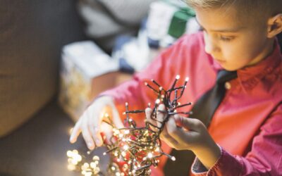 Kleine jongen heeft een snoer kerstlichtjes in z'n handen.