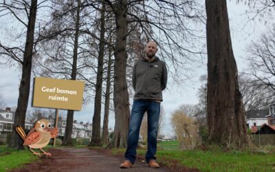 Collega Maurice Biesheuvel tussen bomen in Capelle. Met een vogel die een bord omhoog houdt met de tekst geef bomen ruimte.