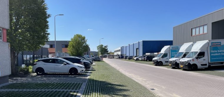 Straat op een industrieterrein met groene, waterdoorlatende parkeerplekken.