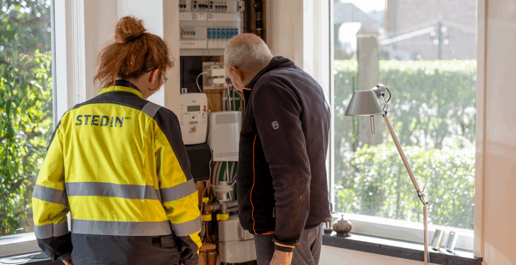 Een monteur van Stedin kijkt met een bewoner in diens meterkast.