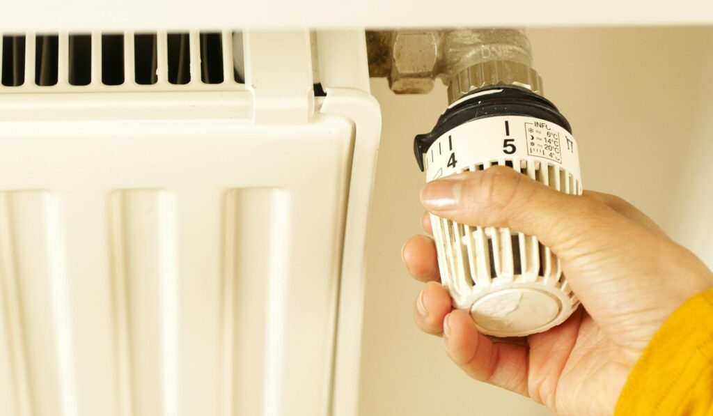 Hand draait aan de verwarmingsknop.