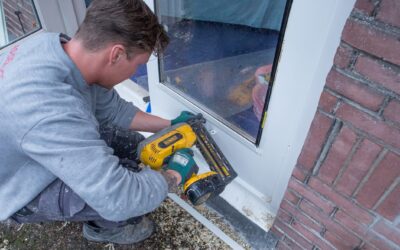 Man is op z'n hurken bezig isolatieglas in een tuindeur te plaatsen.