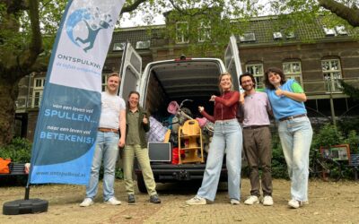 Medewerkers van Ontspulknul staan bij hun bus met een beachvlag erbij