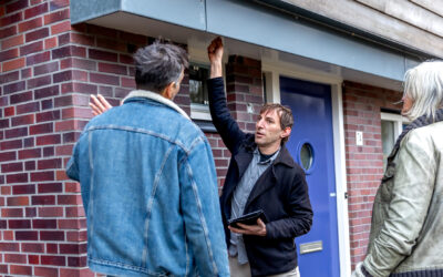 Buren kijken naar de buitenkant van hun pand. Een man voelt aan een muur.