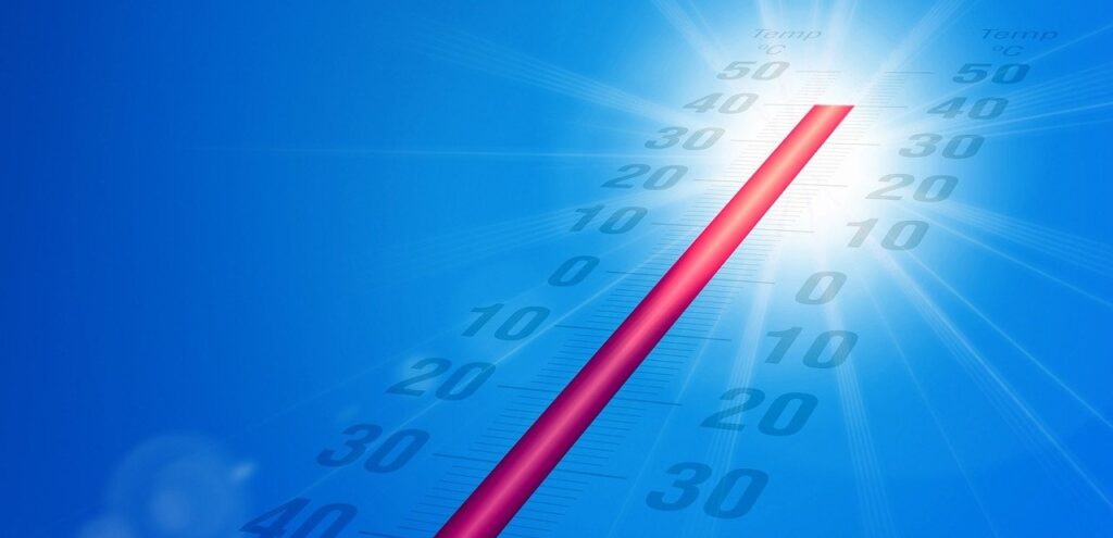 Blauwe lucht met rode thermometer die aangeeft dat het flink heet is.