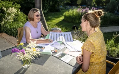 Tuinranger Hanneke in gesprek met op tafel materialen uit de informatiemap van de Tuinrangers