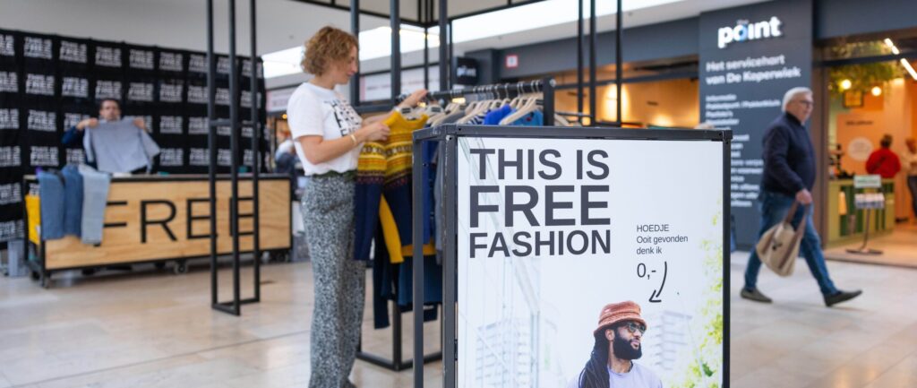 Een vrouw kijkt in de kledingrekken van Free Fashion in de Koperwiek.