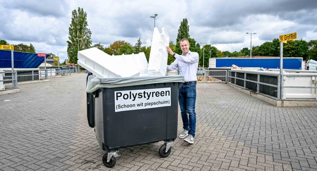 Wethouder Sjoerd Geissler bij de nieuwe inzamelstroom EPS op de Milieustraat. Hij staat met veel piepschuim bij een container.