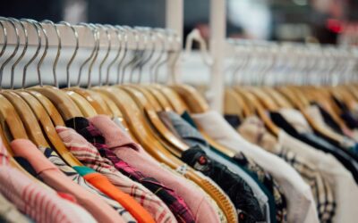 Kledingrek van dichtbij met veel hangertjes en overhemden daaraan.