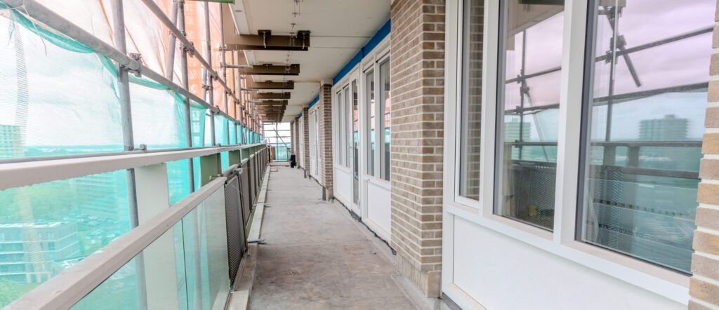 Galerij van flatgebouw in de steigers met nieuwe kunststof kozijnen.