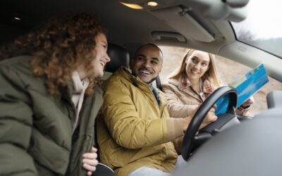Twee jonge mensen in een auto. En iemand staat ernaast met een routekaart.